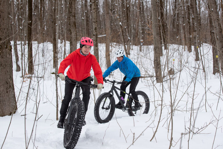 Women with fat tires biking in the snow.
