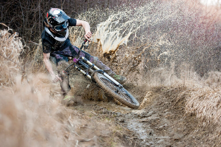 A cyclist drifting in a mud splashing water.