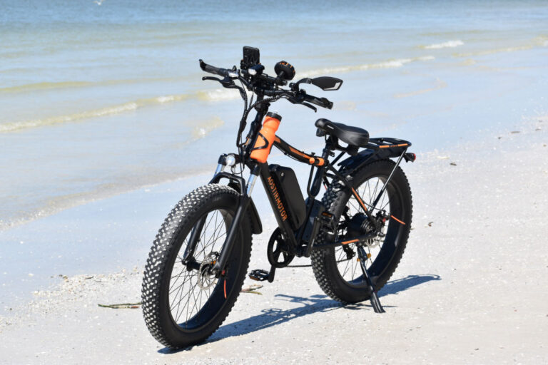An Electronic bike on a seashore with a kickstand.