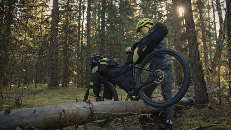 A woman going over a log with her mountain bike.