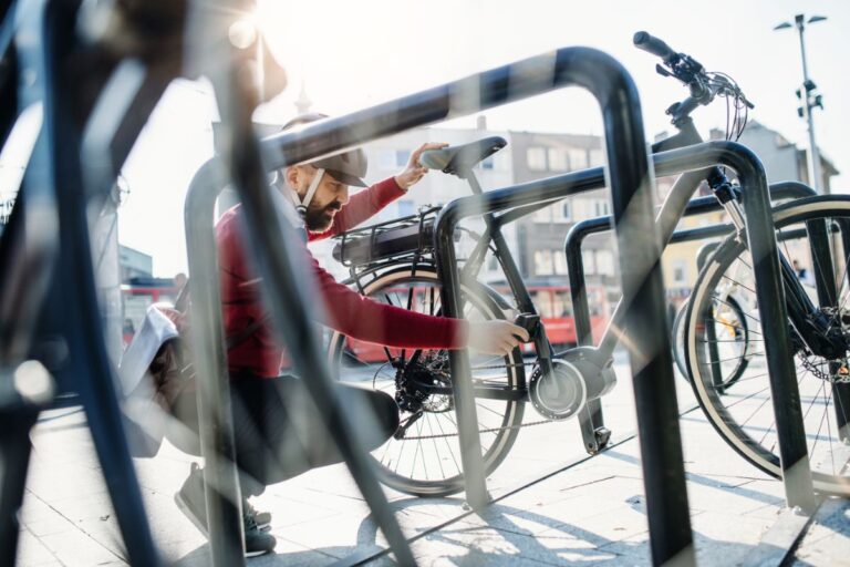A man holding a pedal of an electric bike on a rack.