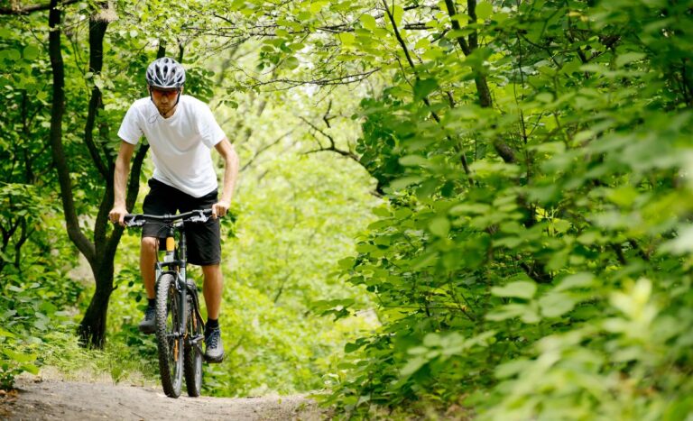 A man cycling in a forest trail with his bike.